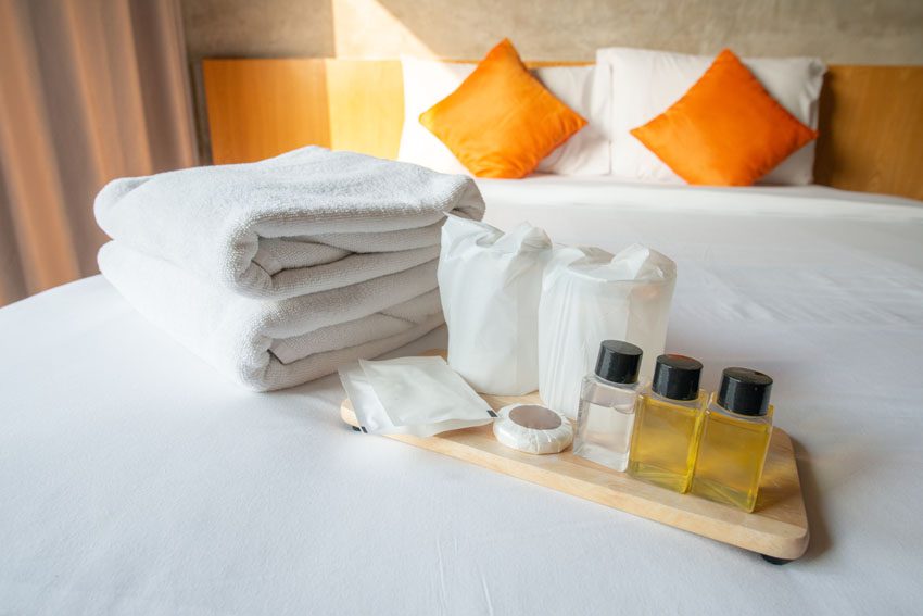 Set of hotel amenities (such as towels, shampoo, soap, drinking glass etc) on the bed. Hotel amenities is something of a premium nature provided in addition to the room when renting a room, ManagedBNB
